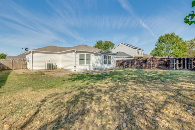 back of house featuring a lawn, a fenced backyard, and central AC