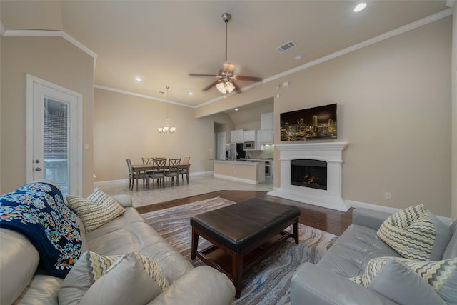 living room featuring crown molding, ceiling fan with notable chandelier, and light hardwood / wood-style floors