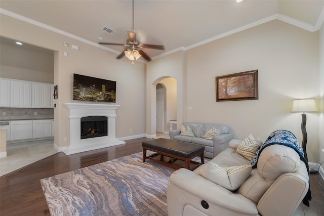 living room featuring dark hardwood / wood-style flooring, crown molding, lofted ceiling, and ceiling fan