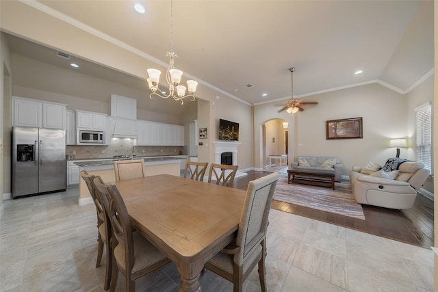 dining area with an inviting chandelier, ornamental molding, lofted ceiling, and sink