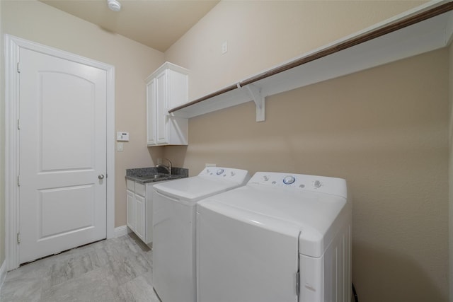 clothes washing area with sink, washer and clothes dryer, and cabinets