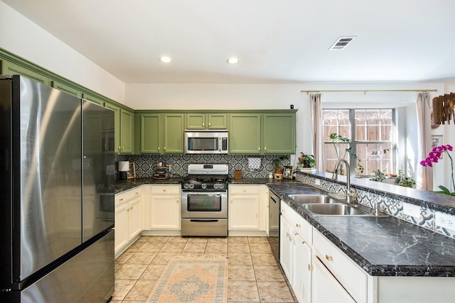 kitchen featuring sink, light tile patterned floors, green cabinets, stainless steel appliances, and backsplash