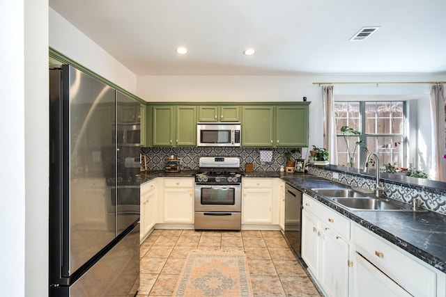 kitchen with tasteful backsplash, sink, green cabinetry, and appliances with stainless steel finishes