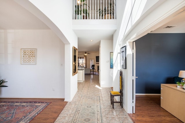 hallway with a towering ceiling and light wood-type flooring