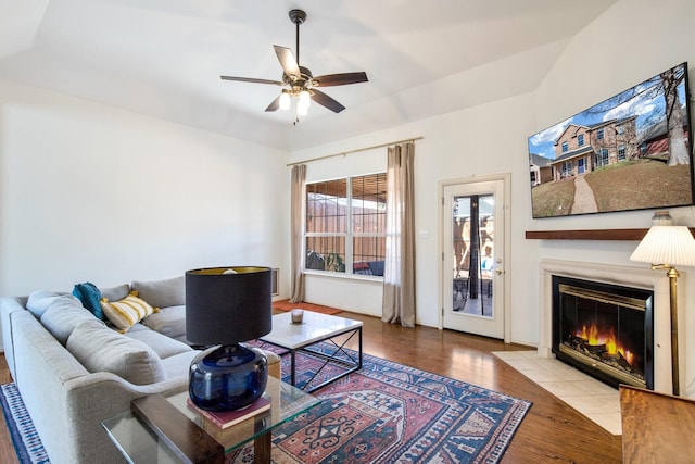 living room with a tiled fireplace, ceiling fan, and light hardwood / wood-style floors