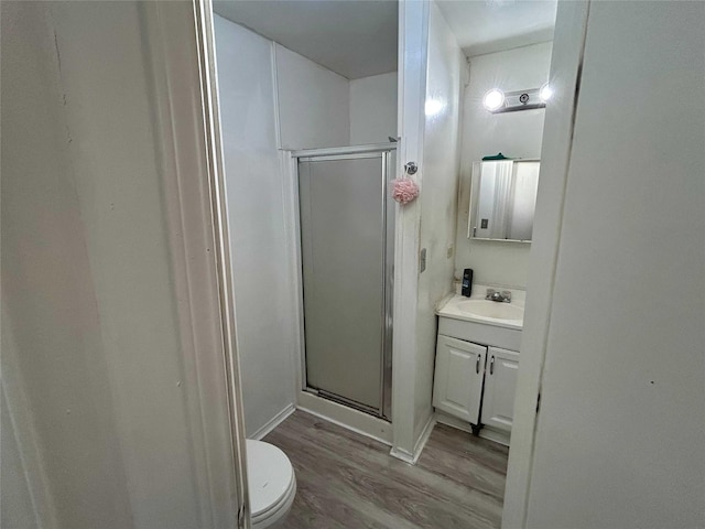 bathroom with toilet, vanity, a shower with door, and hardwood / wood-style floors