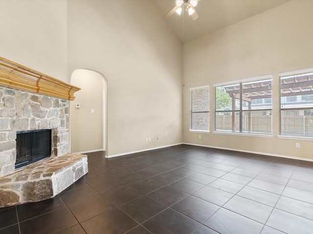 unfurnished living room with dark tile patterned flooring, a stone fireplace, high vaulted ceiling, and ceiling fan