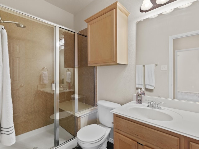 bathroom featuring vanity, a shower with shower door, and toilet