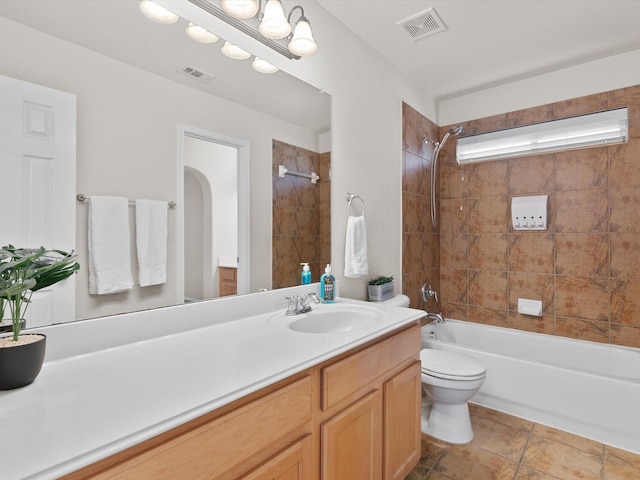 full bathroom featuring tiled shower / bath, vanity, and toilet