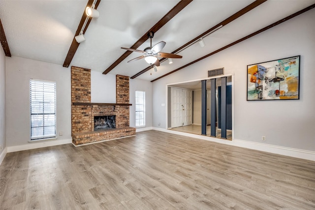 unfurnished living room with lofted ceiling with beams, plenty of natural light, light hardwood / wood-style flooring, and a brick fireplace