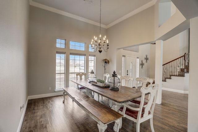 dining room with a towering ceiling, ornamental molding, dark hardwood / wood-style flooring, and a notable chandelier