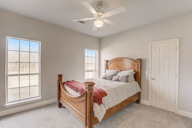 bedroom featuring multiple windows, light colored carpet, and ceiling fan