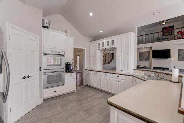 kitchen featuring white cabinetry, sink, double oven, and kitchen peninsula