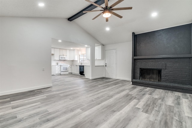 unfurnished living room with high vaulted ceiling, beamed ceiling, ceiling fan, a brick fireplace, and light hardwood / wood-style flooring