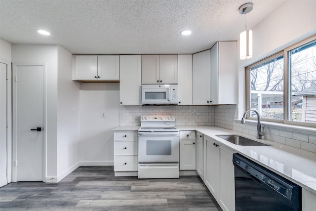 kitchen with sink, white cabinets, hanging light fixtures, light hardwood / wood-style floors, and white appliances