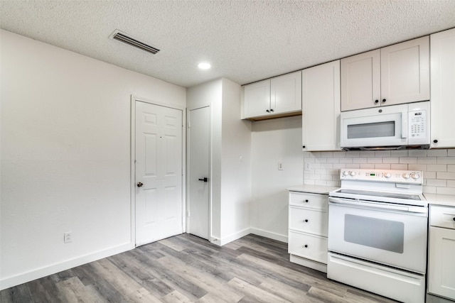 kitchen featuring white appliances, light wood-type flooring, and white cabinets