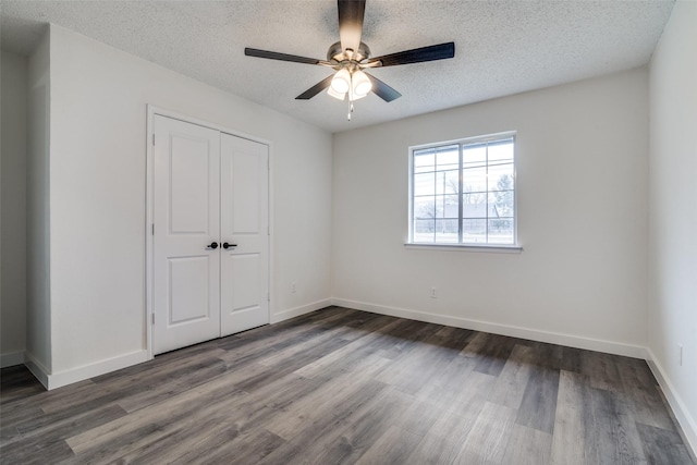 unfurnished bedroom featuring ceiling fan, dark wood-type flooring, a textured ceiling, and a closet