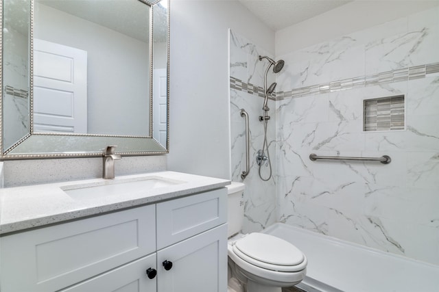 bathroom with vanity, toilet, and a tile shower