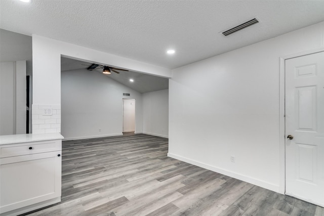 unfurnished room with ceiling fan, lofted ceiling, a textured ceiling, and light wood-type flooring