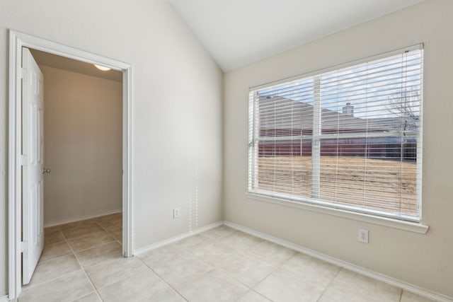 spare room featuring light tile patterned floors, vaulted ceiling, and a wealth of natural light