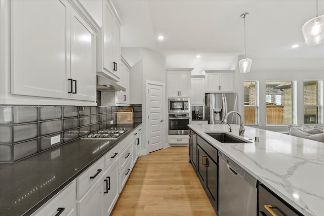 kitchen with sink, white cabinetry, hanging light fixtures, stainless steel appliances, and dark stone counters