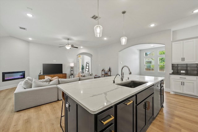 kitchen with white cabinetry, sink, an island with sink, and decorative light fixtures