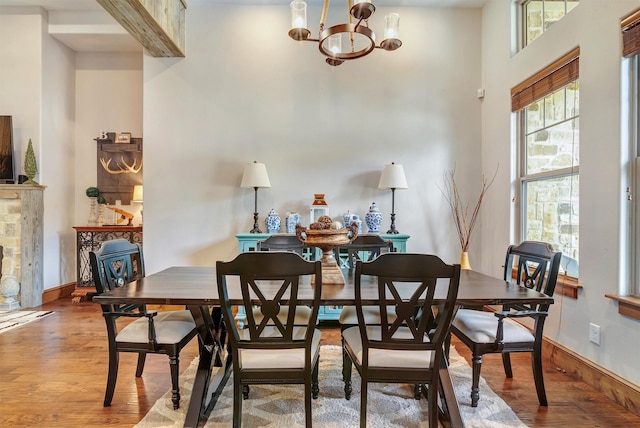 dining room with hardwood / wood-style flooring, a towering ceiling, and a notable chandelier