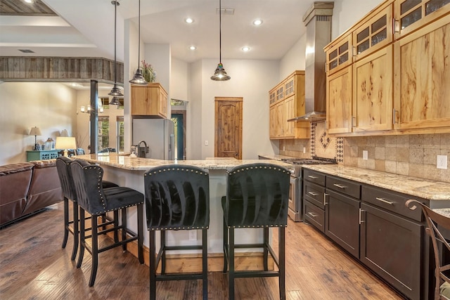 kitchen with a center island with sink, light stone counters, and decorative light fixtures