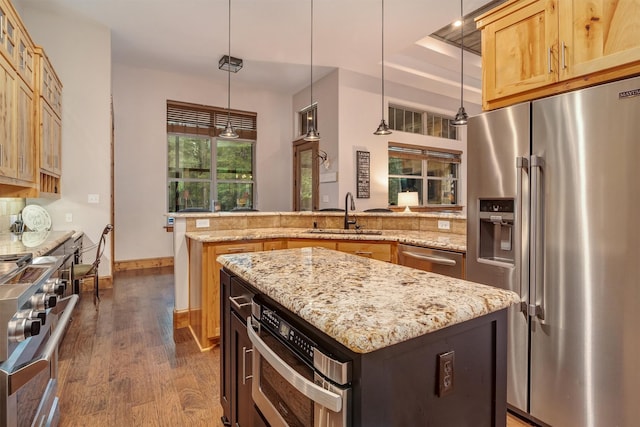 kitchen with high quality appliances, a kitchen island, sink, and decorative light fixtures