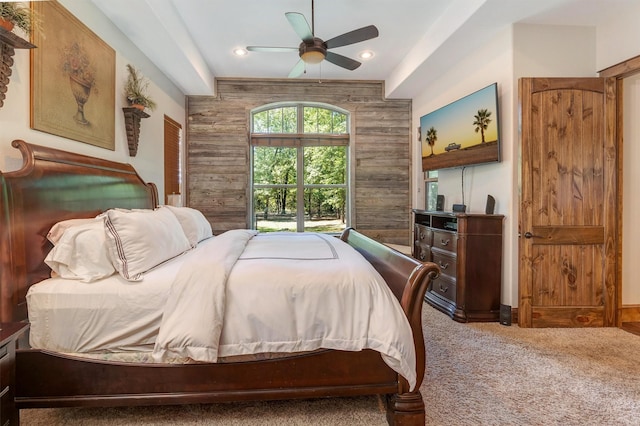 carpeted bedroom featuring ceiling fan and wood walls