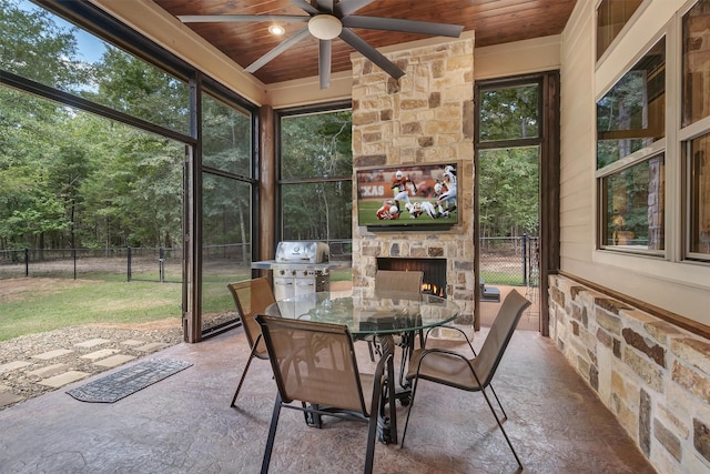 sunroom featuring ceiling fan, wooden ceiling, and an outdoor stone fireplace