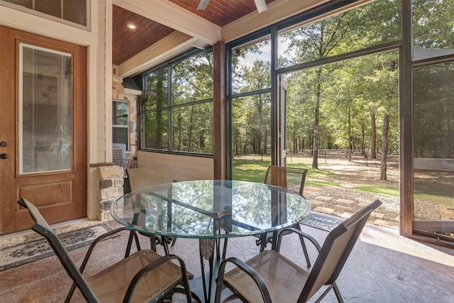 sunroom featuring beam ceiling, wood ceiling, and plenty of natural light