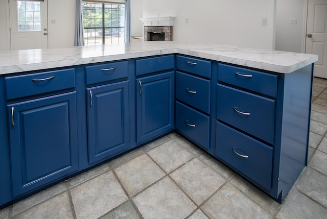 kitchen featuring a fireplace, kitchen peninsula, and blue cabinets