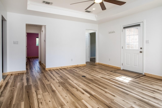 interior space with ceiling fan, wood-type flooring, a raised ceiling, and a wealth of natural light