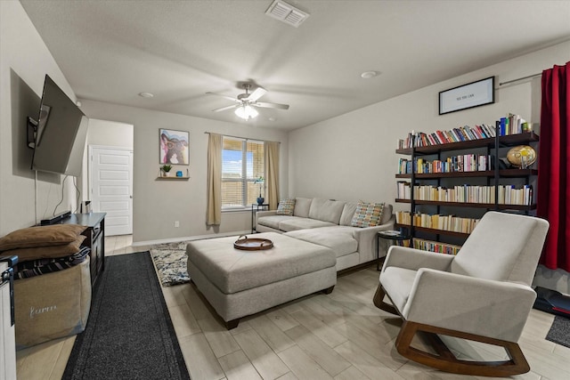 living area with a ceiling fan, light wood-style floors, and baseboards