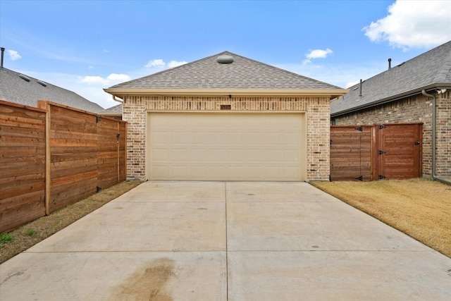 view of front of home with roof with shingles, brick siding, driveway, and fence