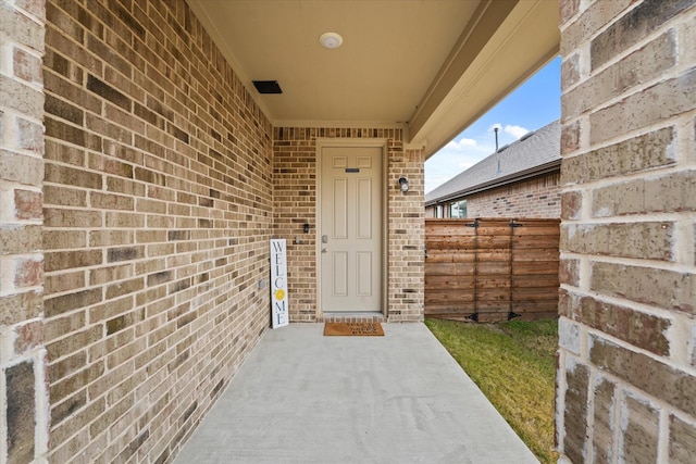 doorway to property with brick siding and fence