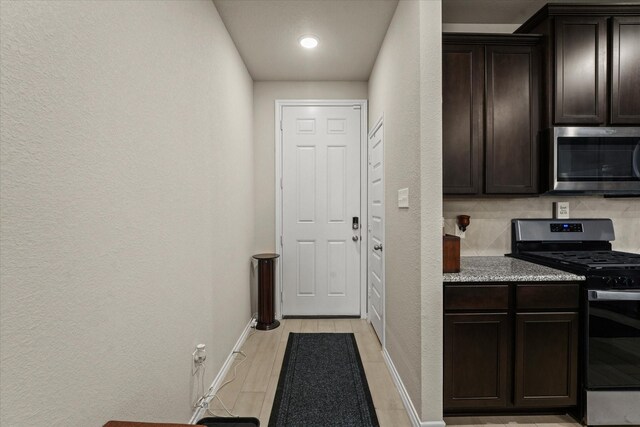 kitchen featuring tasteful backsplash, stainless steel appliances, dark brown cabinets, and light wood-type flooring