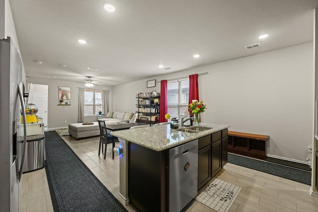 kitchen with stainless steel appliances, a sink, plenty of natural light, recessed lighting, and a center island with sink
