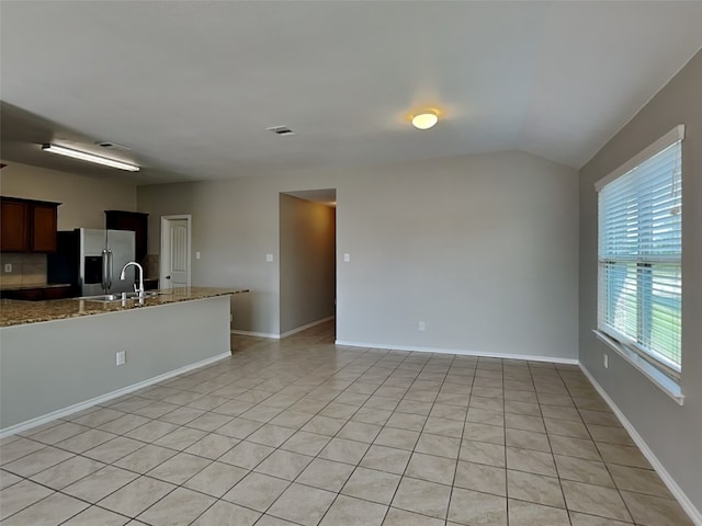 2002 Grimes Dr, Forney, TX 75126 - kitchen featuring stainless steel fridge with ice dispenser, a sink, light tile patterned floors, lofted ceiling, and stone counters