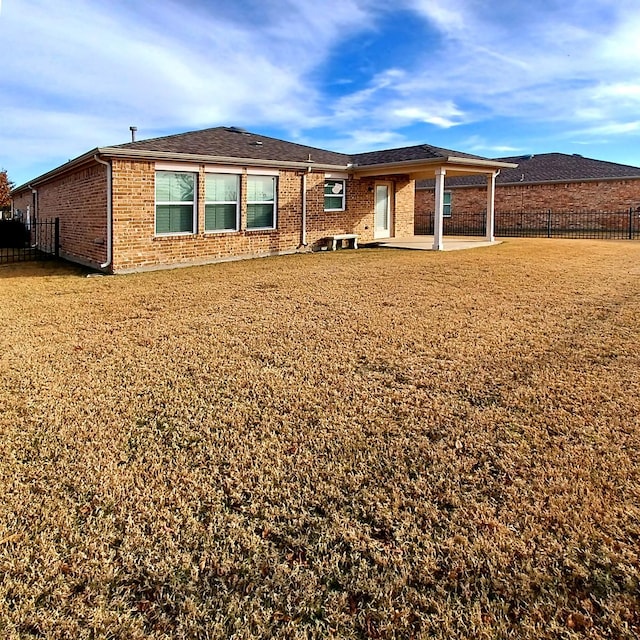 back of house featuring a lawn and a patio