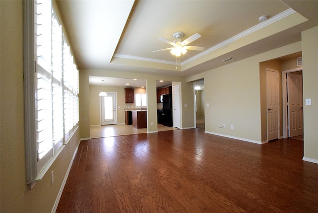 unfurnished living room featuring hardwood / wood-style floors, crown molding, a raised ceiling, and ceiling fan