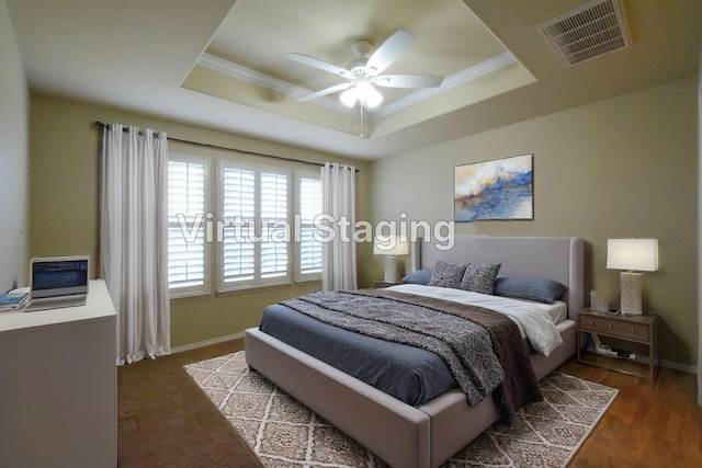 bedroom with dark hardwood / wood-style floors, ornamental molding, and a tray ceiling