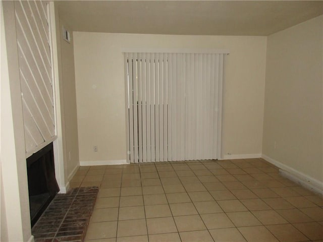 unfurnished living room featuring tile patterned flooring and a brick fireplace