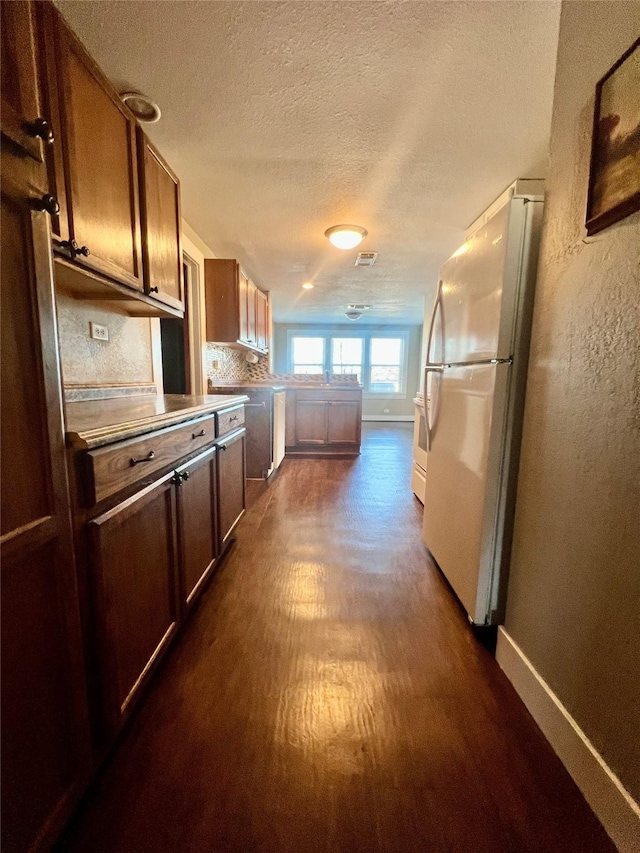 kitchen with backsplash, dark hardwood / wood-style floors, a textured ceiling, and white fridge