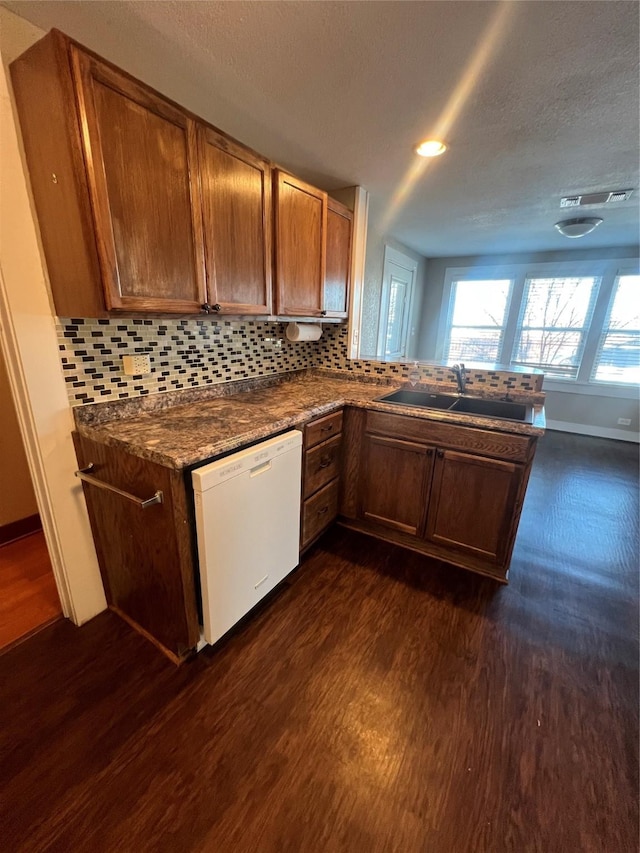 kitchen featuring dishwasher, sink, dark wood-type flooring, and backsplash