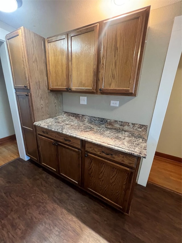 kitchen featuring dark hardwood / wood-style floors and dark stone counters