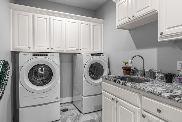 clothes washing area featuring cabinets, sink, and washing machine and dryer