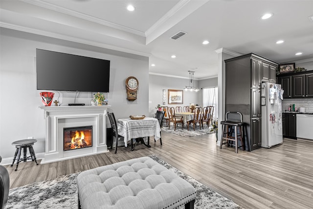 living room with crown molding and light wood-type flooring