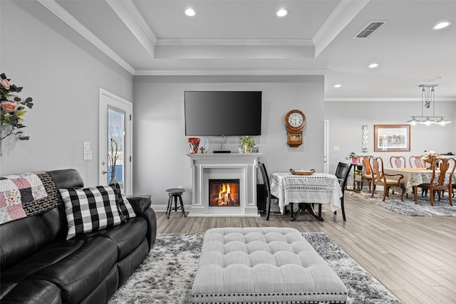 living room featuring crown molding, hardwood / wood-style floors, and a tray ceiling